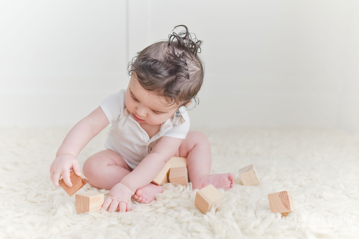 baby+boy+playing+with+wood+blocks+in+white+studio.jpg