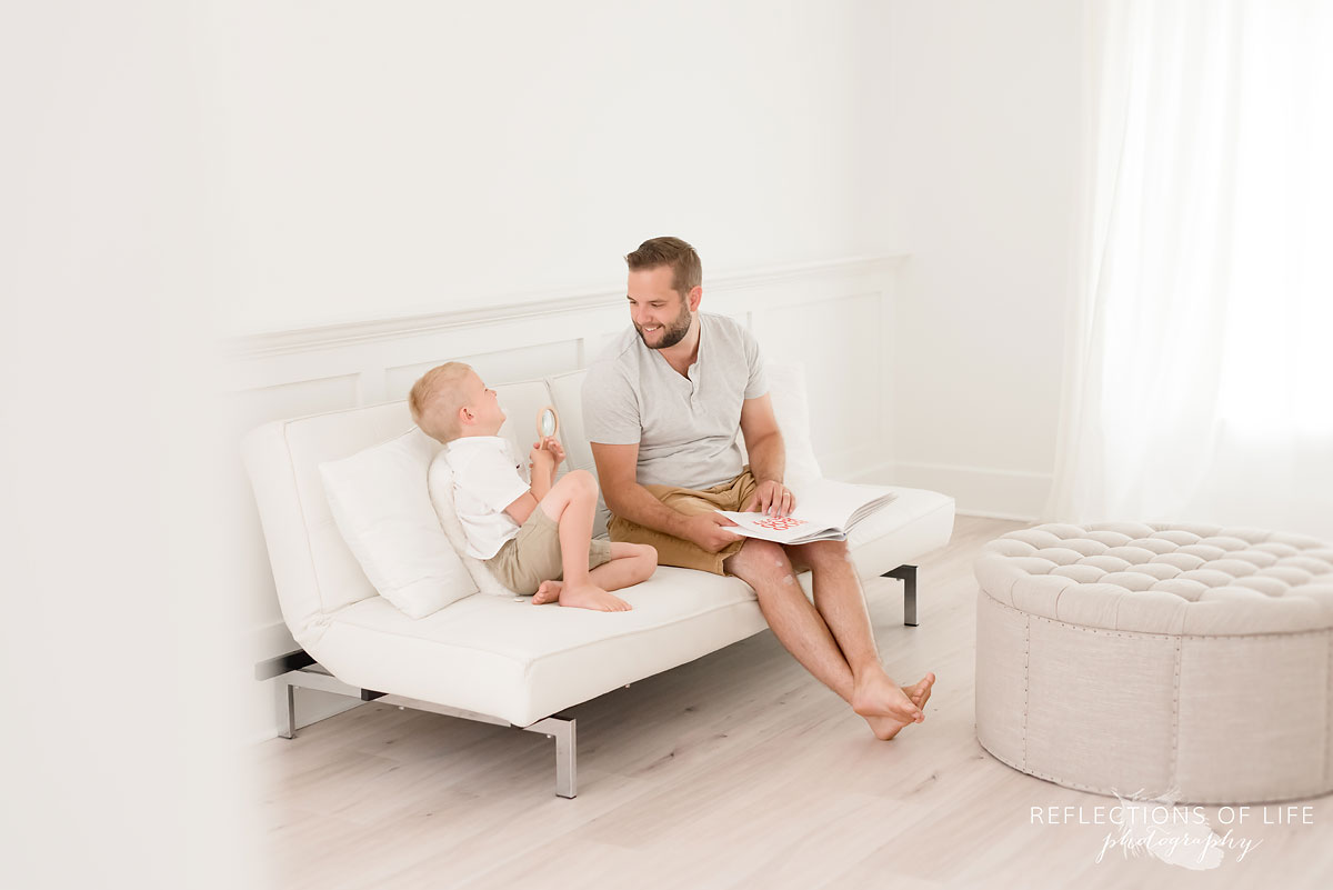 father and son laughing togeher in studio on white couch