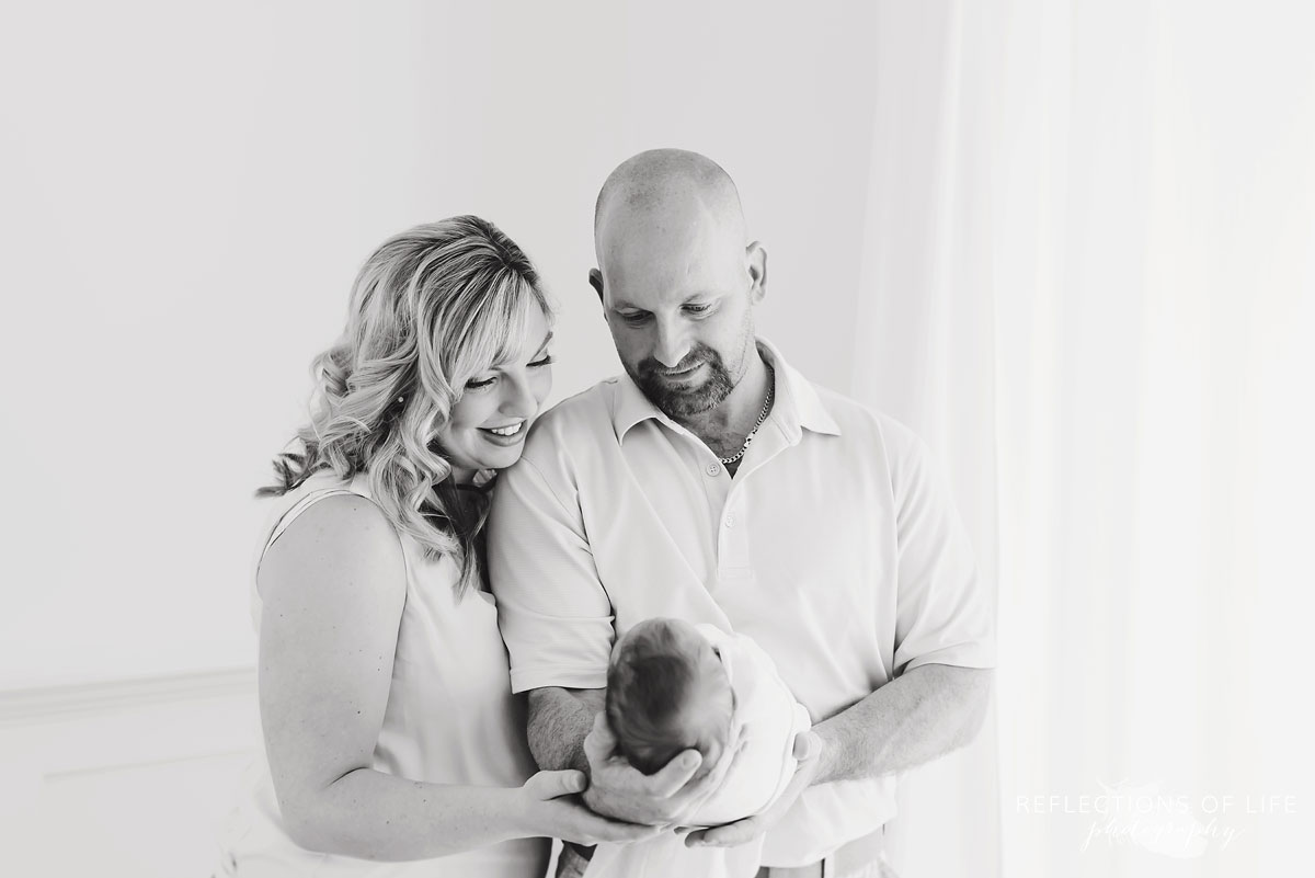 parents looking down holding child black and white