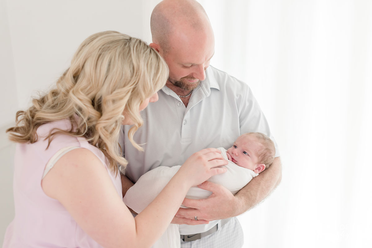 mother and father with baby in white background studio