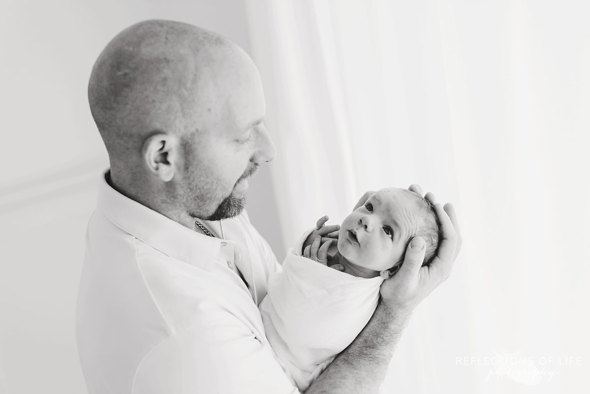 dad holding son in studio black and white