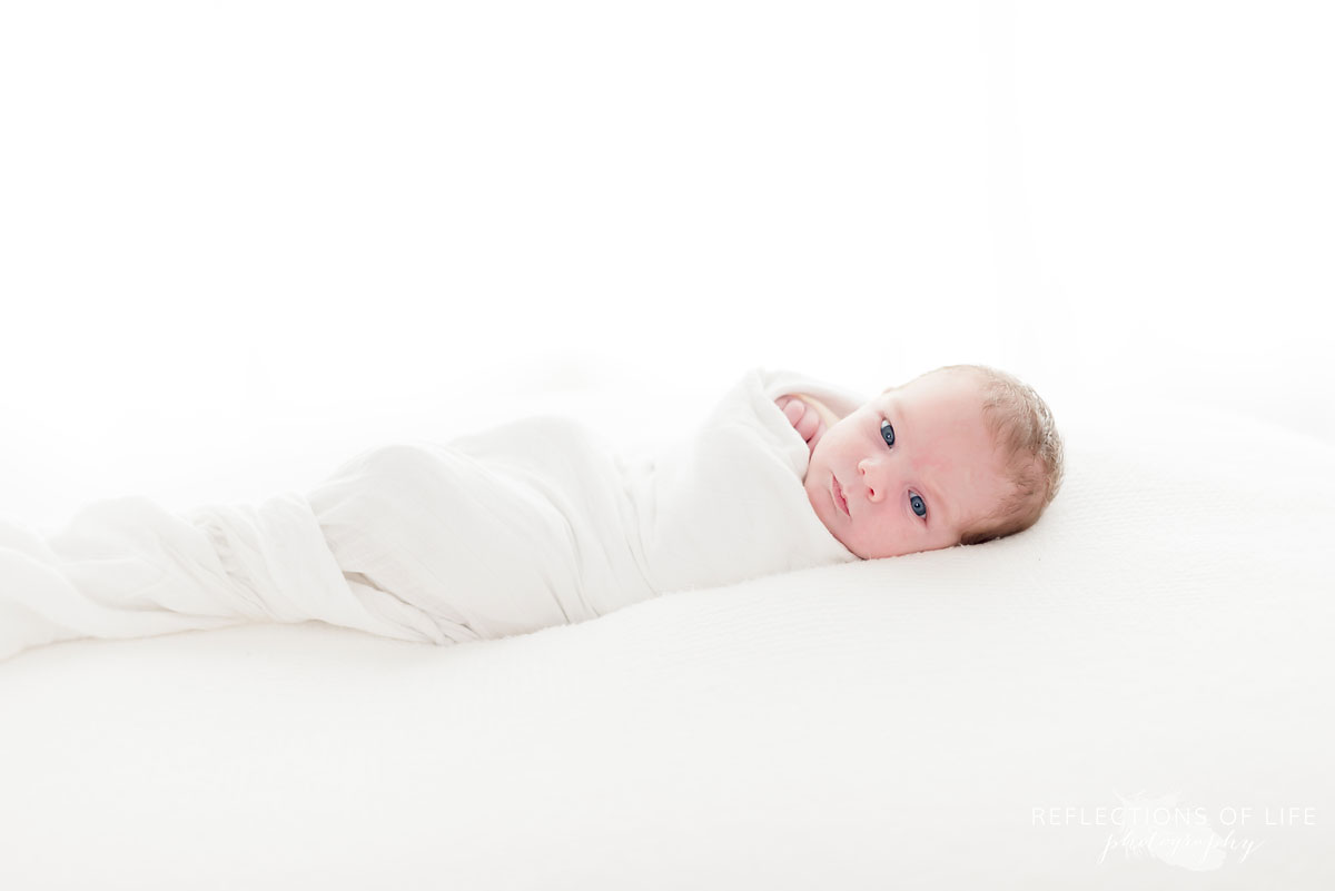 newborn baby on pillow wrapped in blanket
