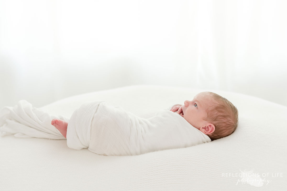 baby boy wrapped in blanket laying on pillow
