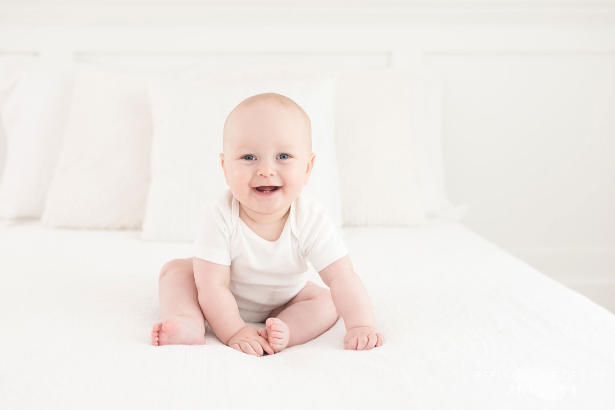baby sitting on white bed in studio.jpg