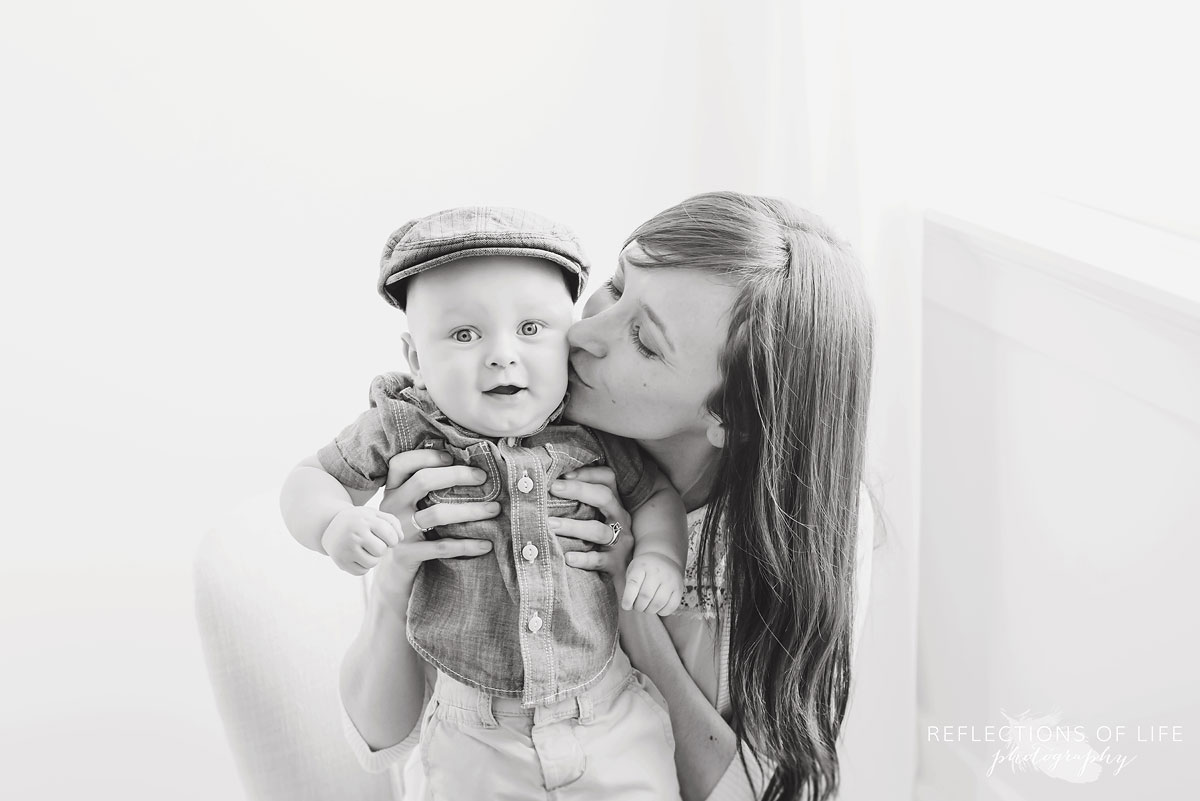 mother giving baby a kiss on the cheek in studio black and white.jpg