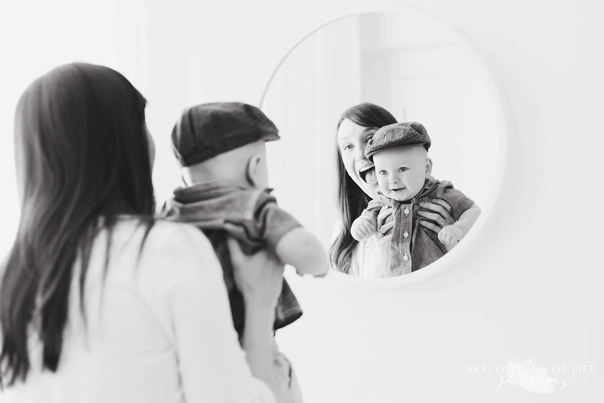 mother holding baby boy up to mirror black and white.jpg