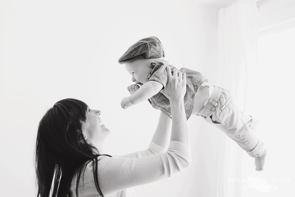 mother lifting baby up in studio black and white.jpg