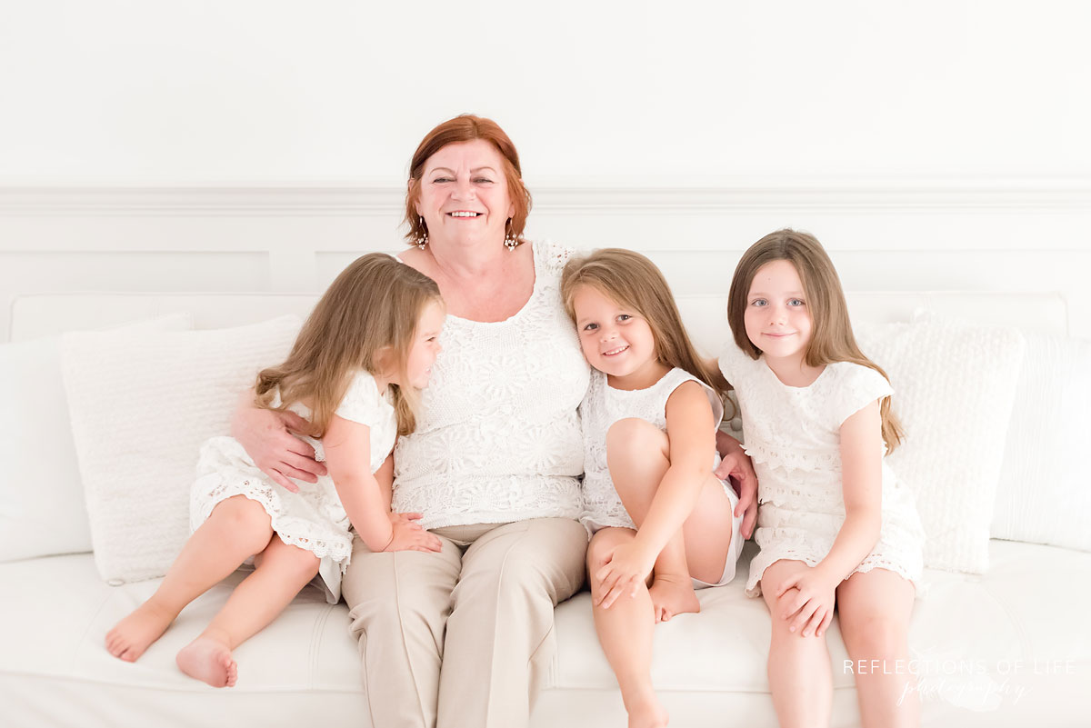 Gorgeous Grandma sitting with her granddaughters in a white natural light studio