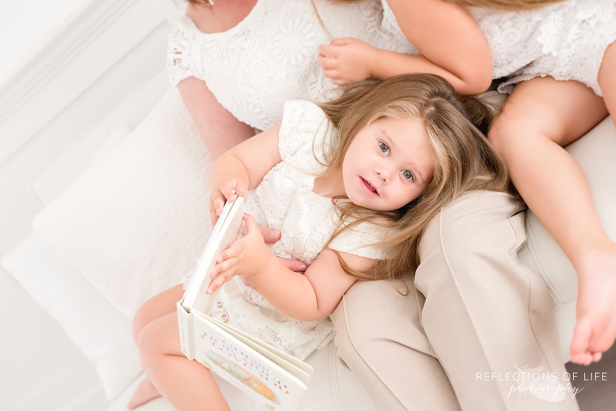 Beautiful portrait of little girl holding a book and looking into the camera lens