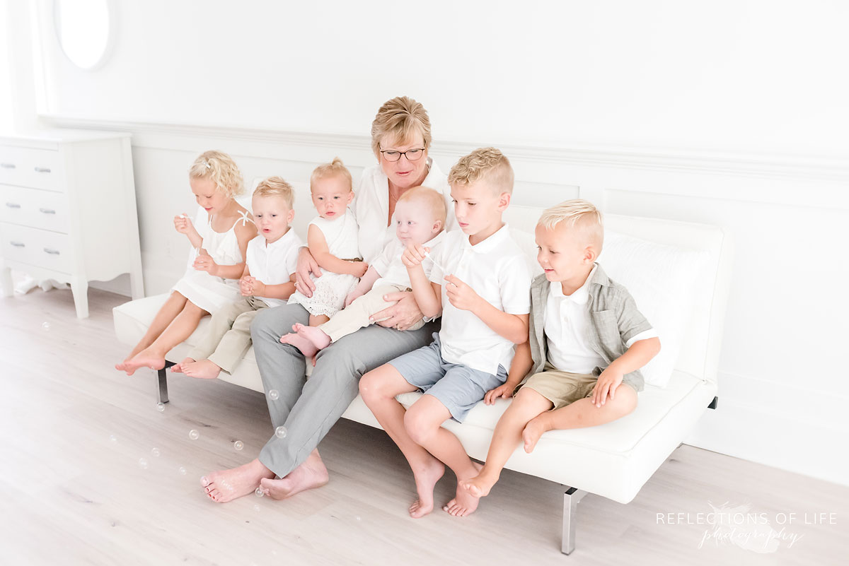 Grandma blowing bubbles with her grandkids in natural light studio