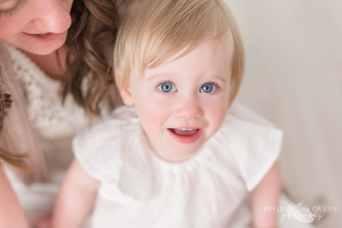 little girl looking up at the camera with wide open blue eyes