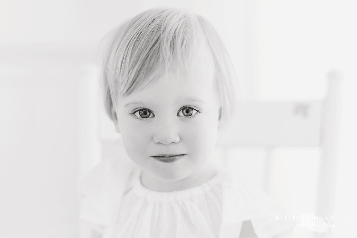 little girl looking straight into the camera in black and white