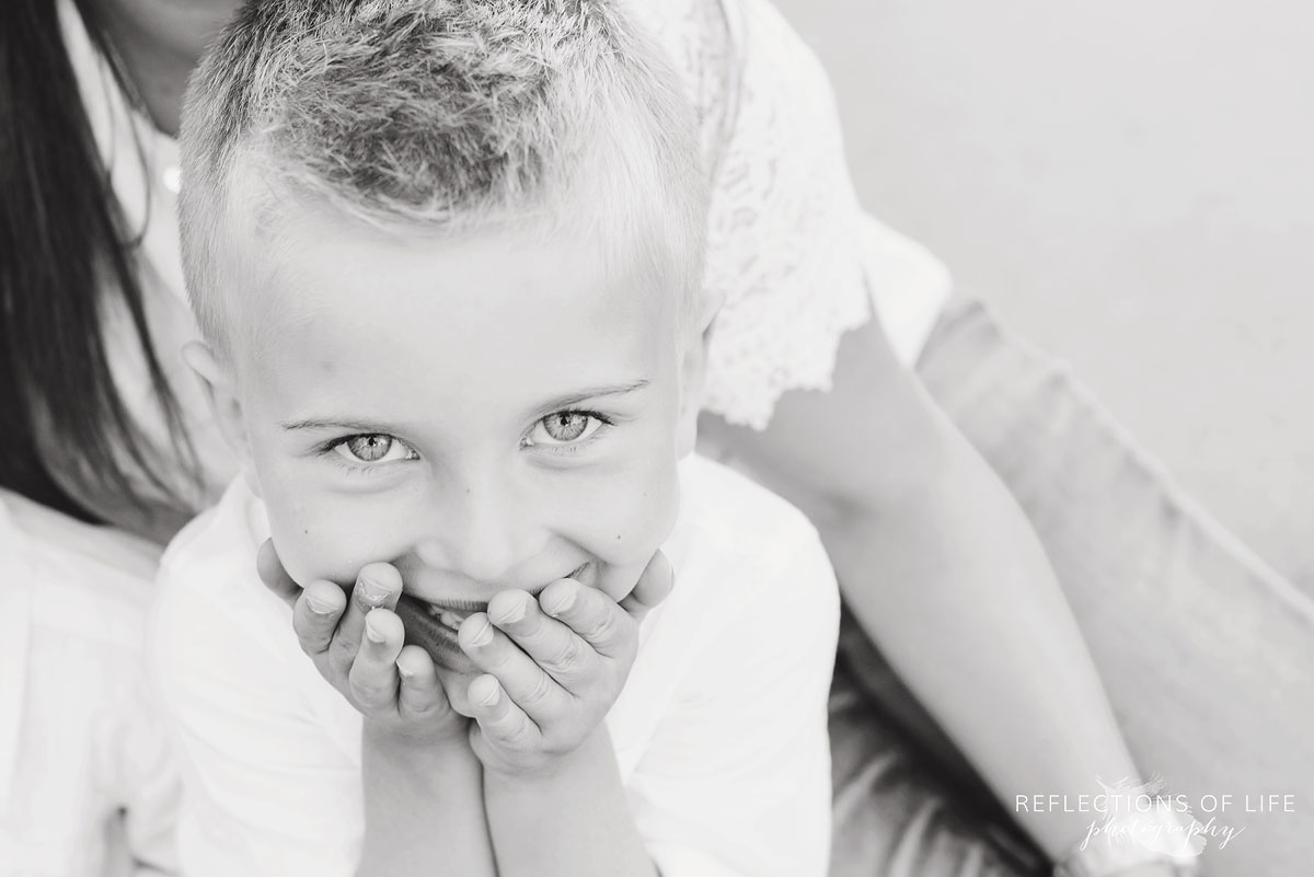 little boy covering his mouth with his hands in black and white