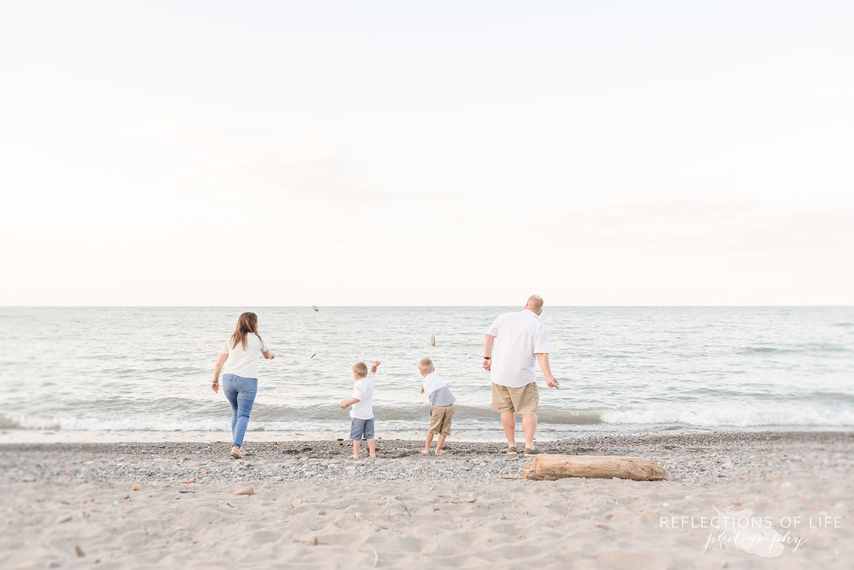 Family throwing rocks into the water at the beach