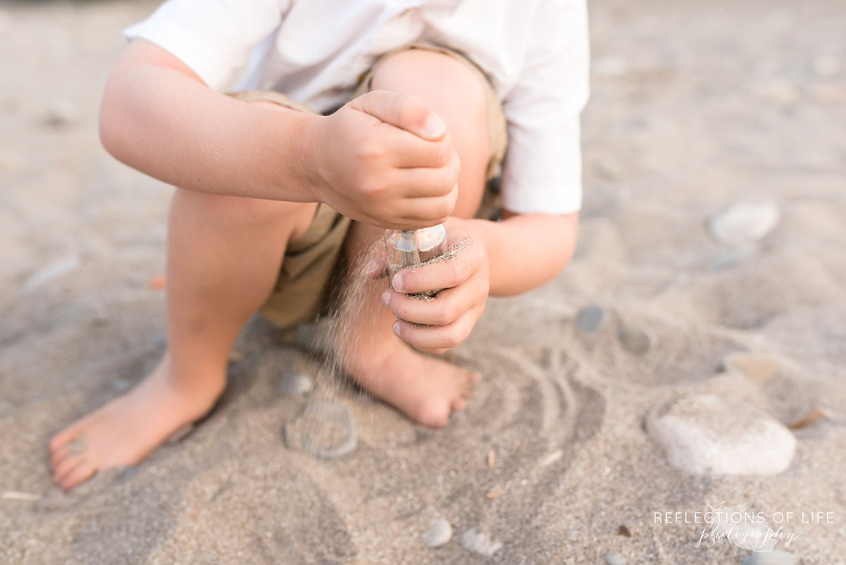 Little boy filling glass bottle with sand at Casablanca Beach
