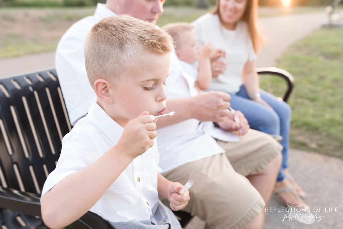 Boy blowing bubbles on the bench at Casablanca Beach in Grimsby