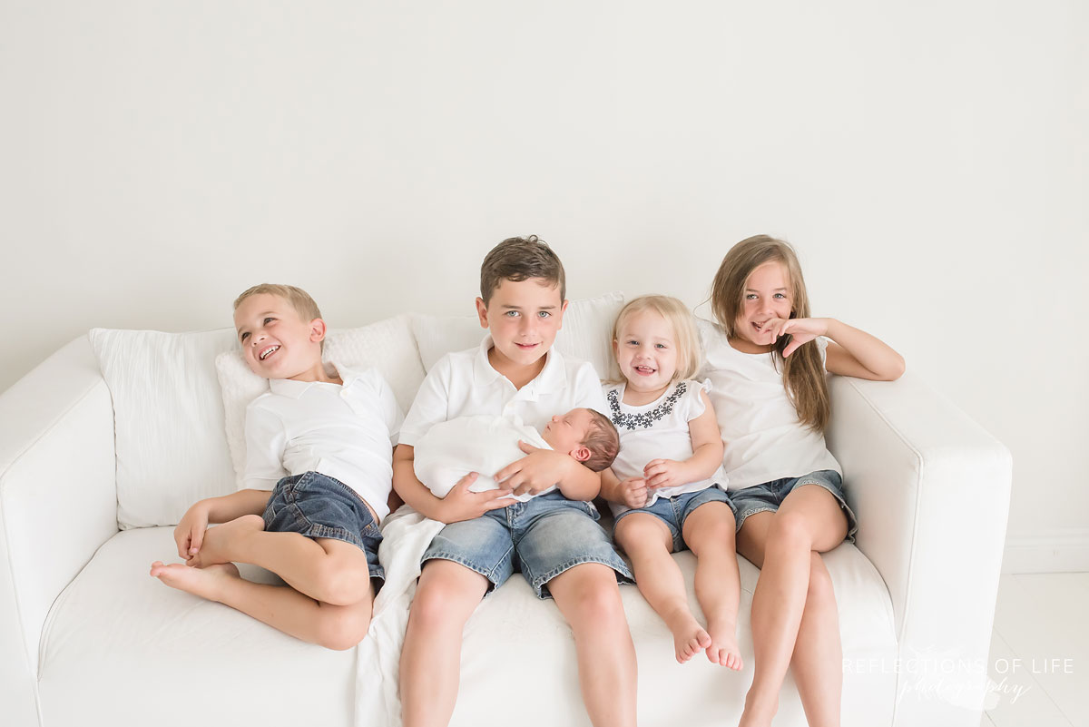 white studio natural light newborn photography in Grimsby Ontario Canada siblings with baby