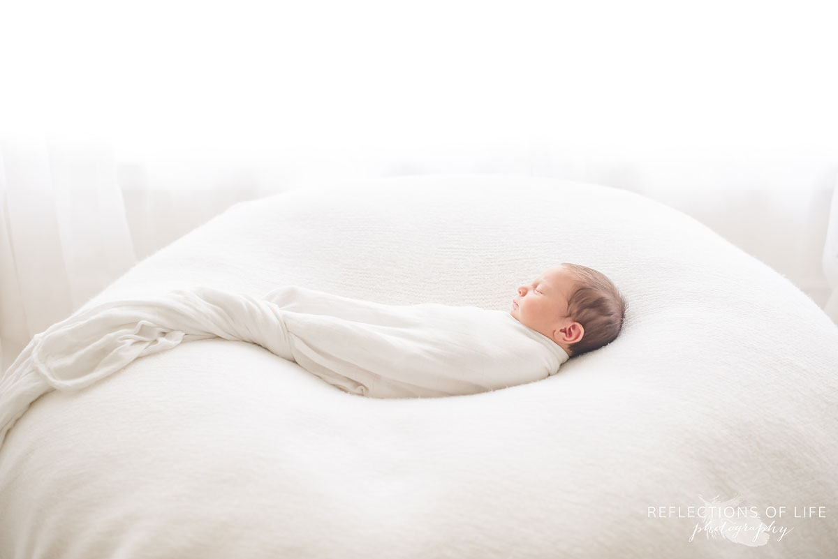 newborn baby boy swaddled in white