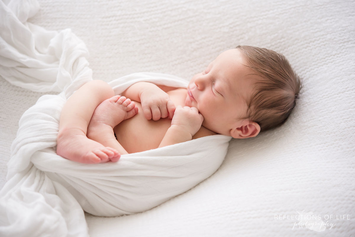newborn baby boy wrapped in white blankets