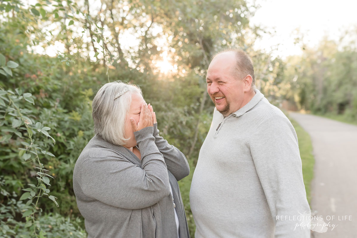 Husband and wife laughing with each other in nature setting