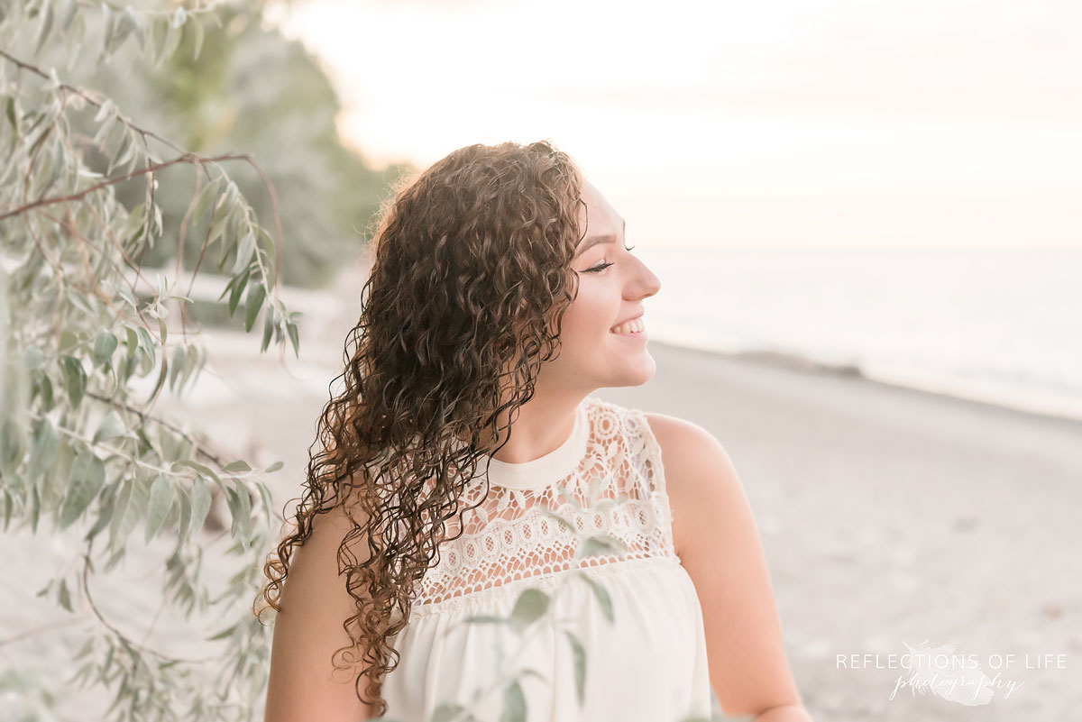 Girl with curly brown hair looking into the water on the beach
