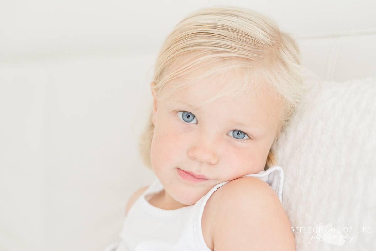 Little girl with blonde hair in white studio