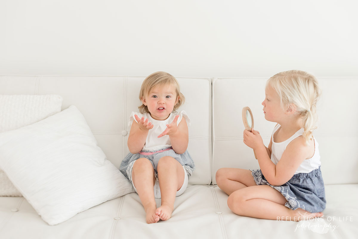 Little girls on white couch with Niagara family photographer