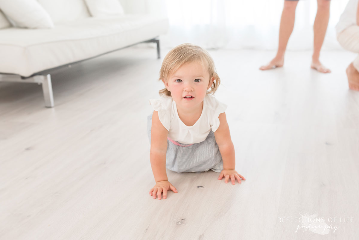 little girl crawling on floor in white studio