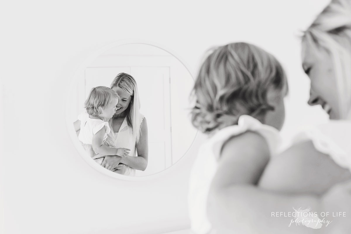 black and white of mom and daughter looking into mirror