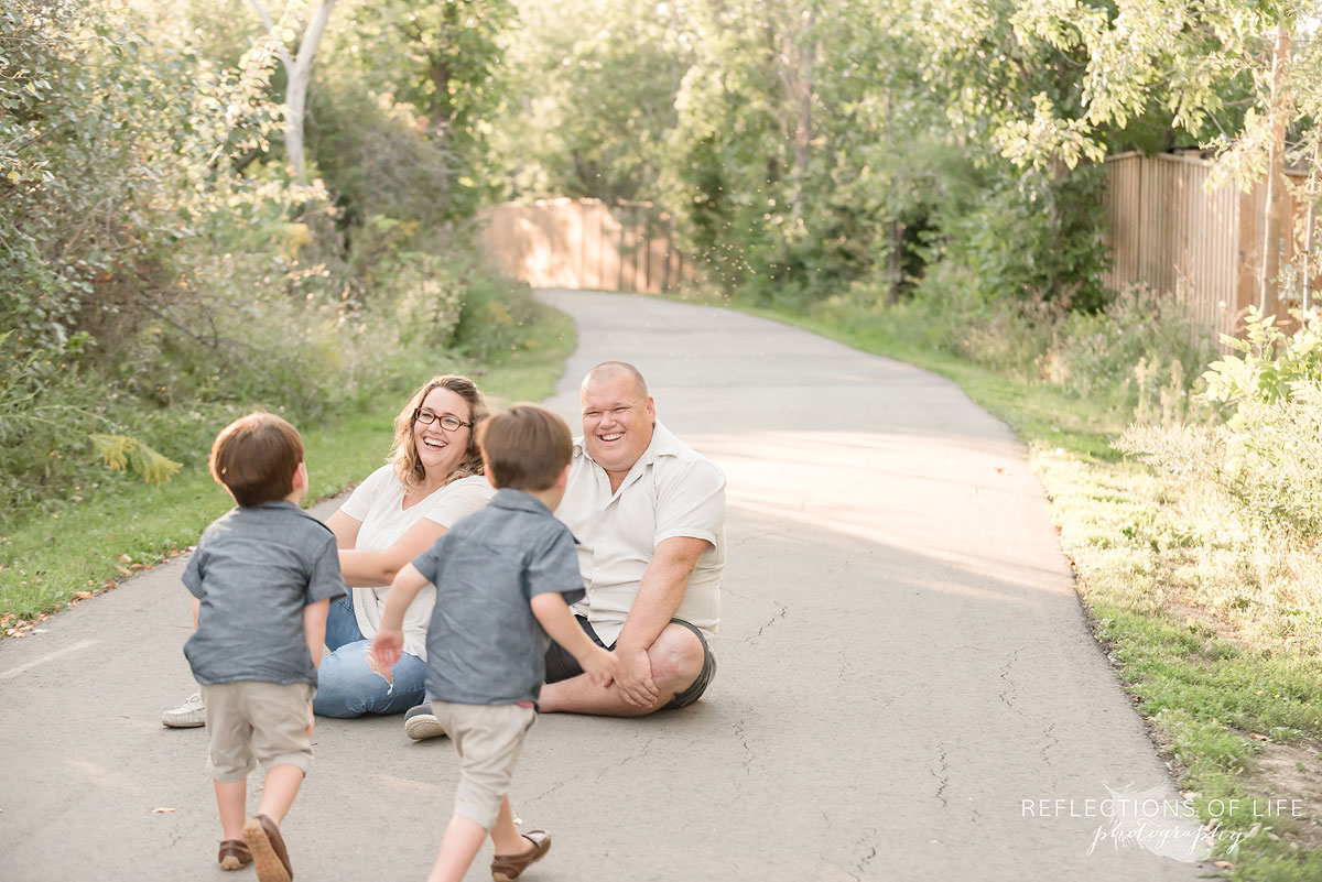 Family of four sitting and running on path