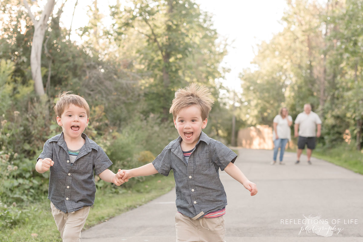 Two boys running, holding hands as parents watch