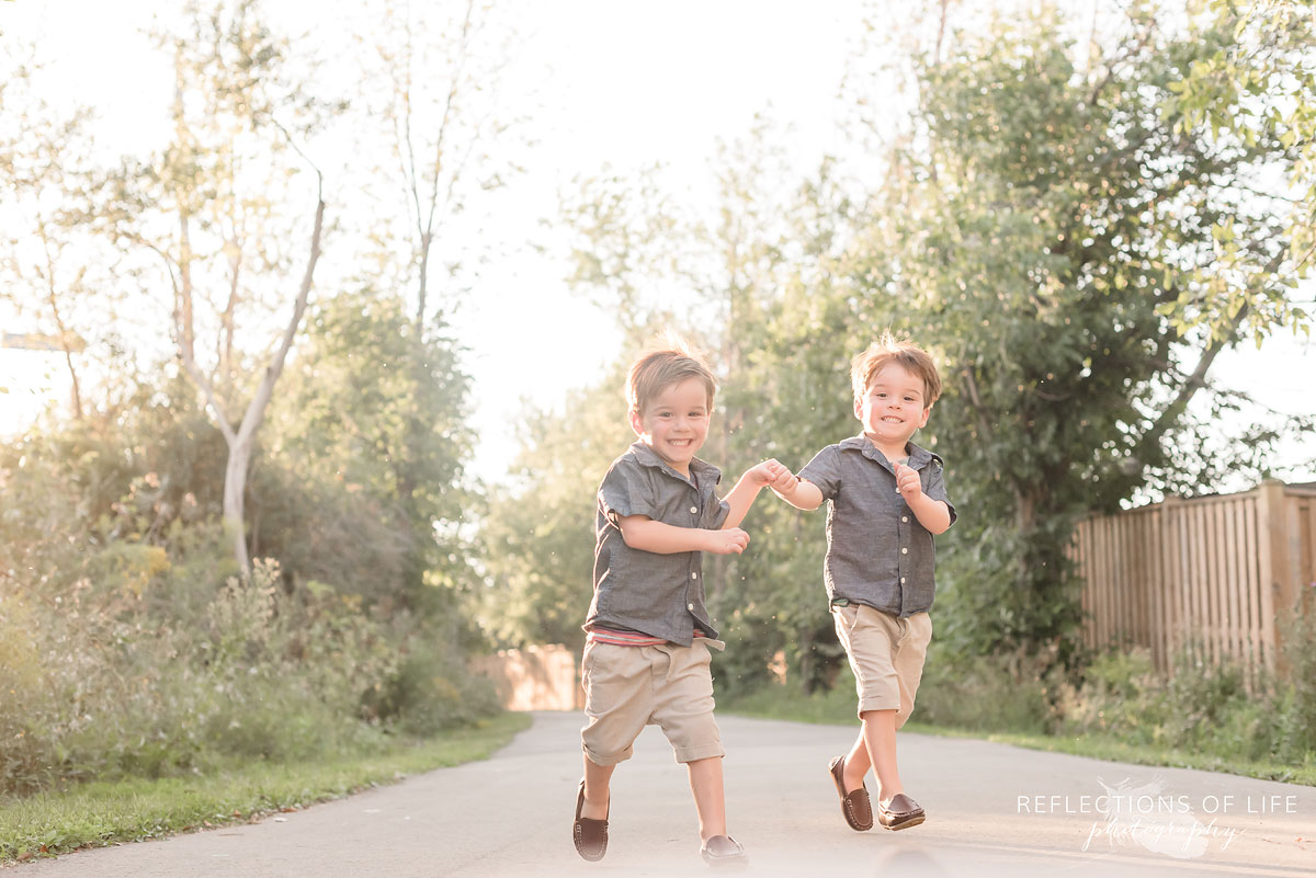 Two boys running down a path and holding hands