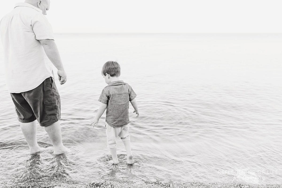 father and son standing in lake black and white