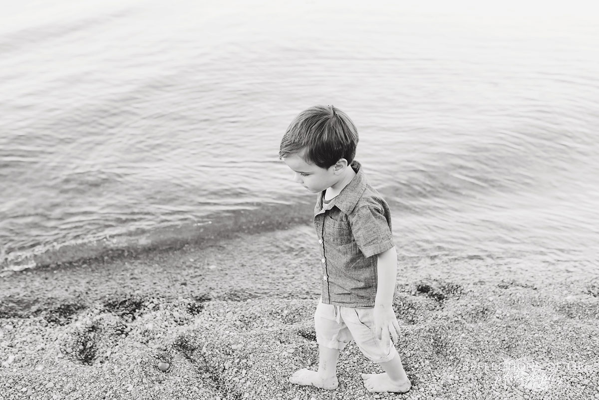 young boy walking down the beach black and white