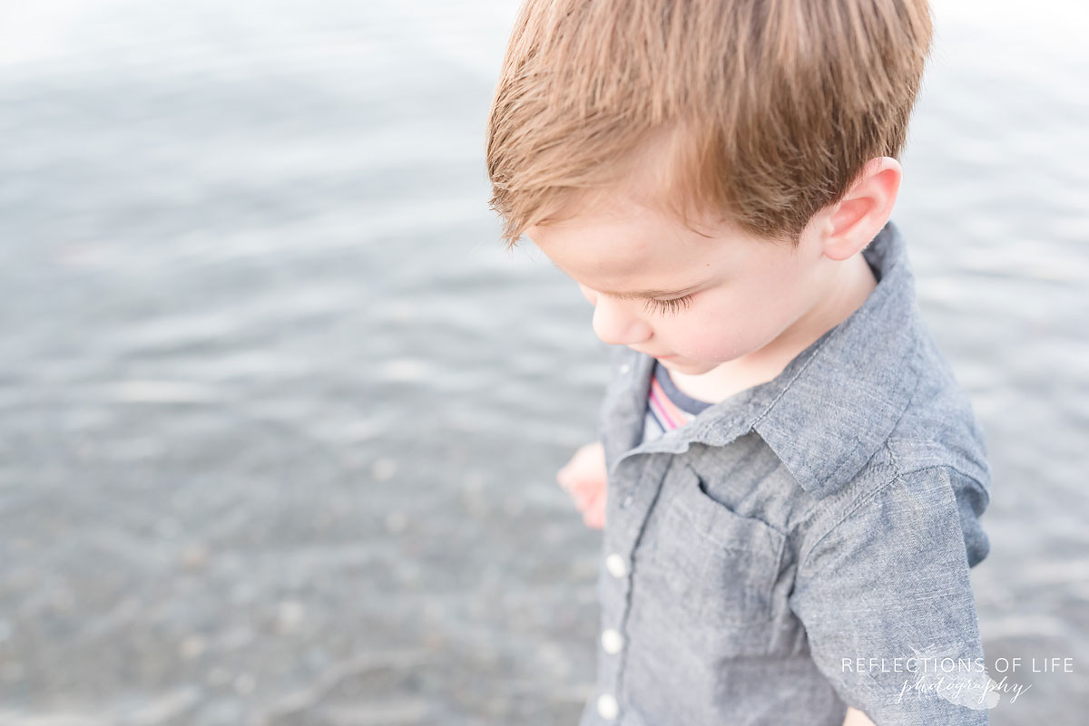 close up shot of a young boy looking down by the water
