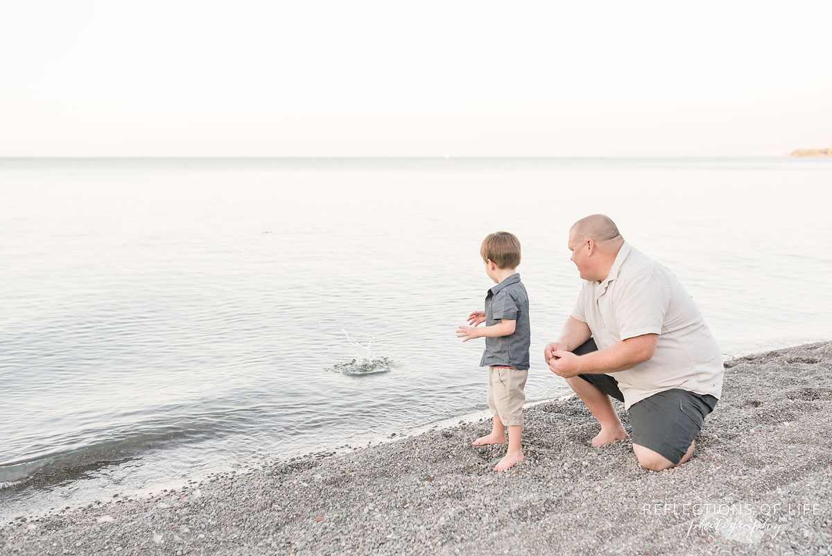father and son throwing rocks into the water