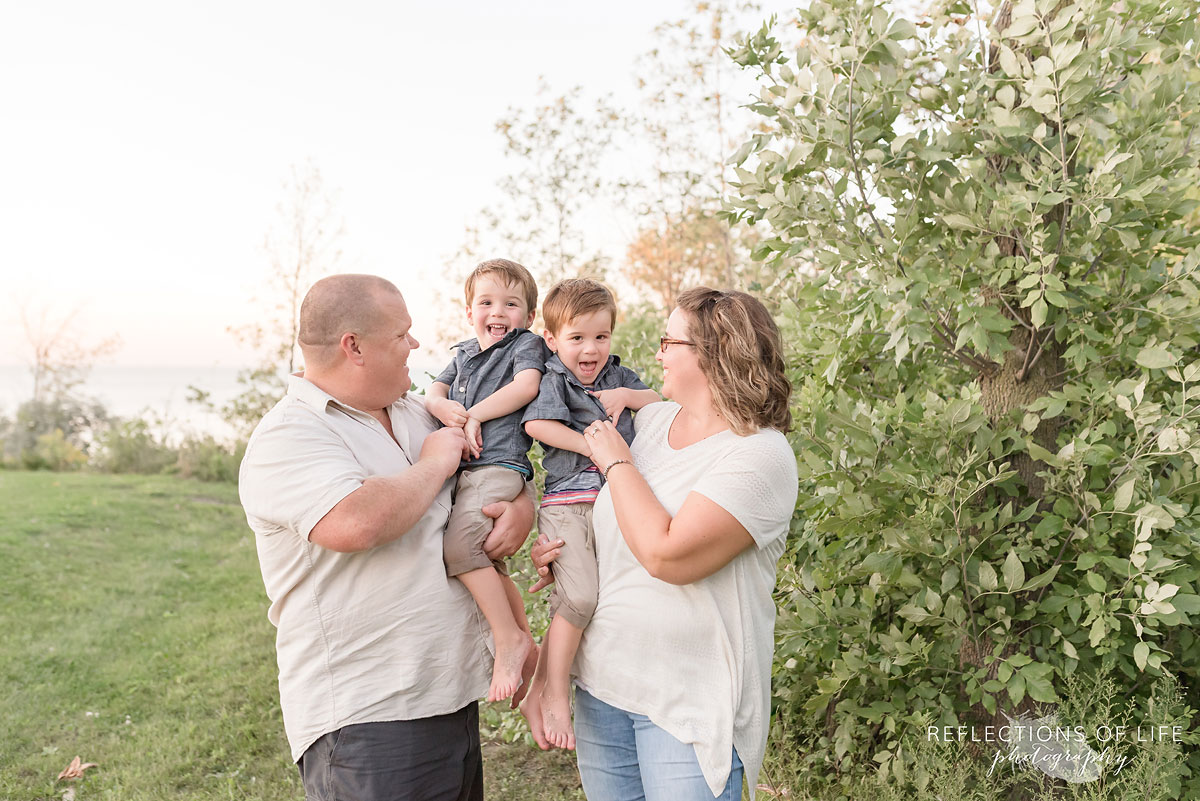 family of four parents holding children laughing and smiling