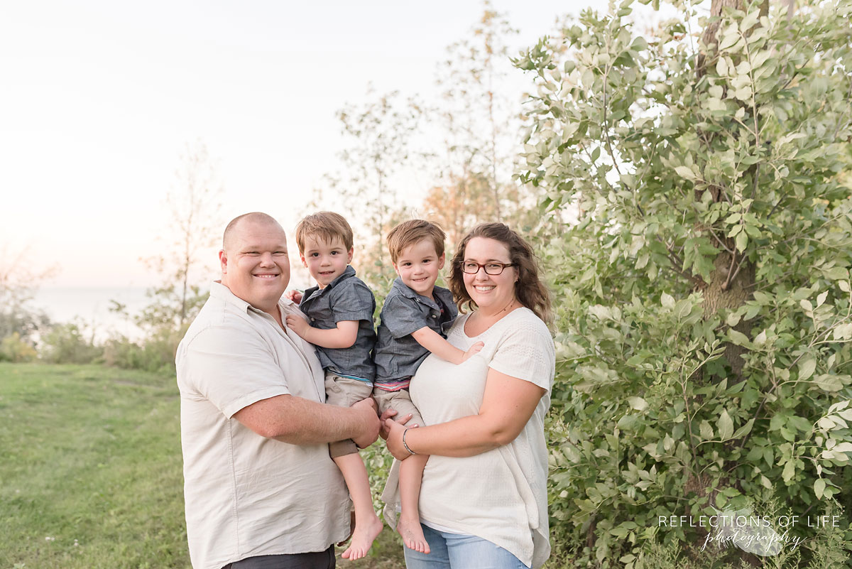 two boys being held by their parents smiling