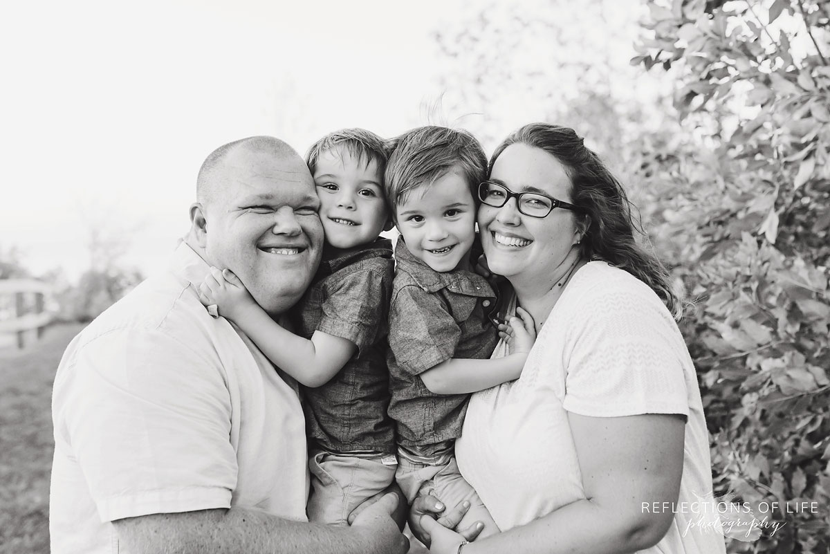 family of four smiling and hugging each other black and white