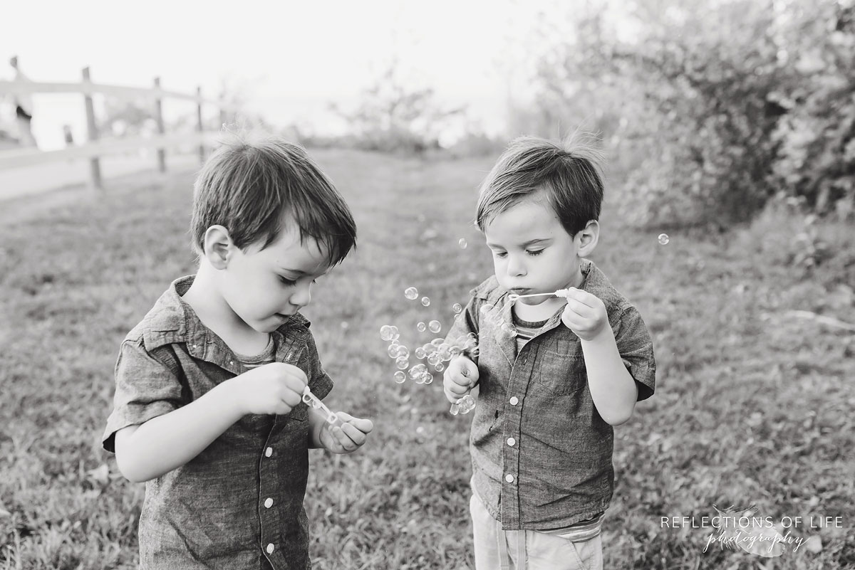 two young boys blowing bubbles black and white by Karen Byker