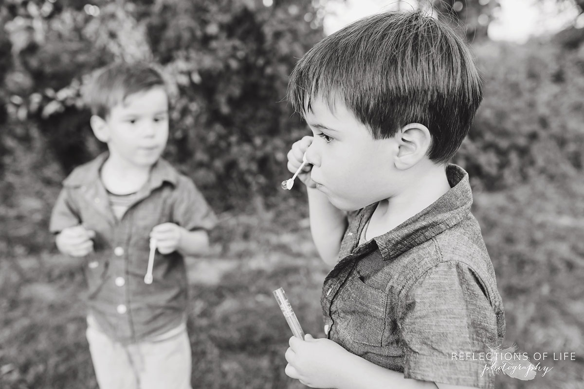 two boys blowing and playing with bubbles black and white