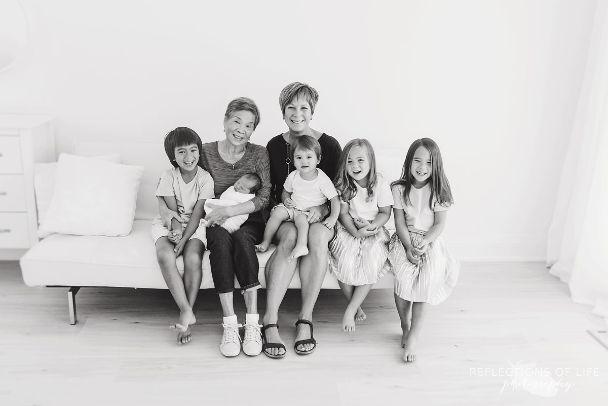 two grandmothers smile with their five grandchildren black and white