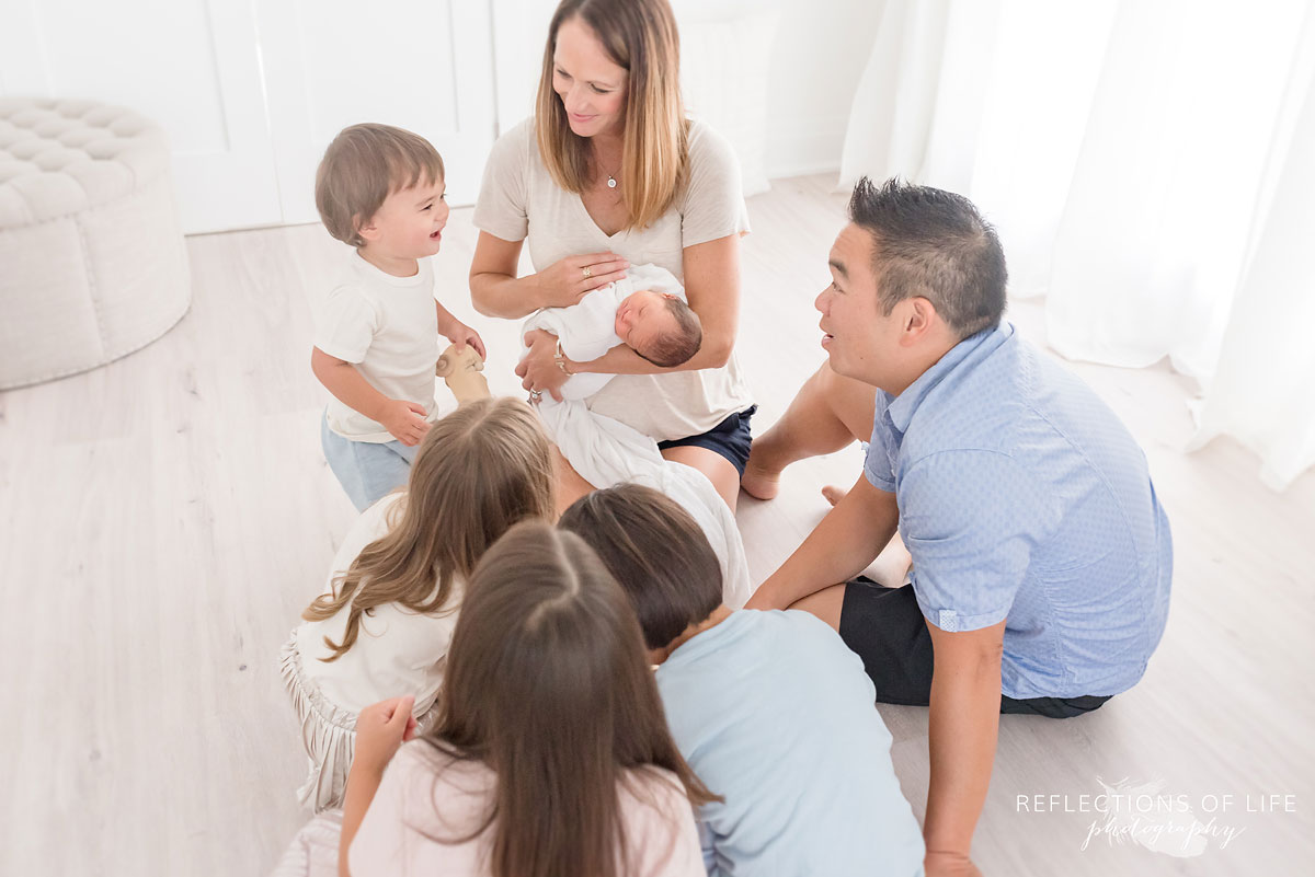 family of seven sitting on the floor in a studio looking at each other happy