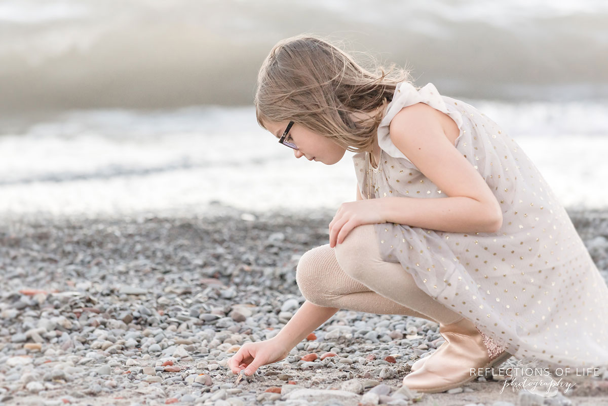 little girl looking at rocks on beach