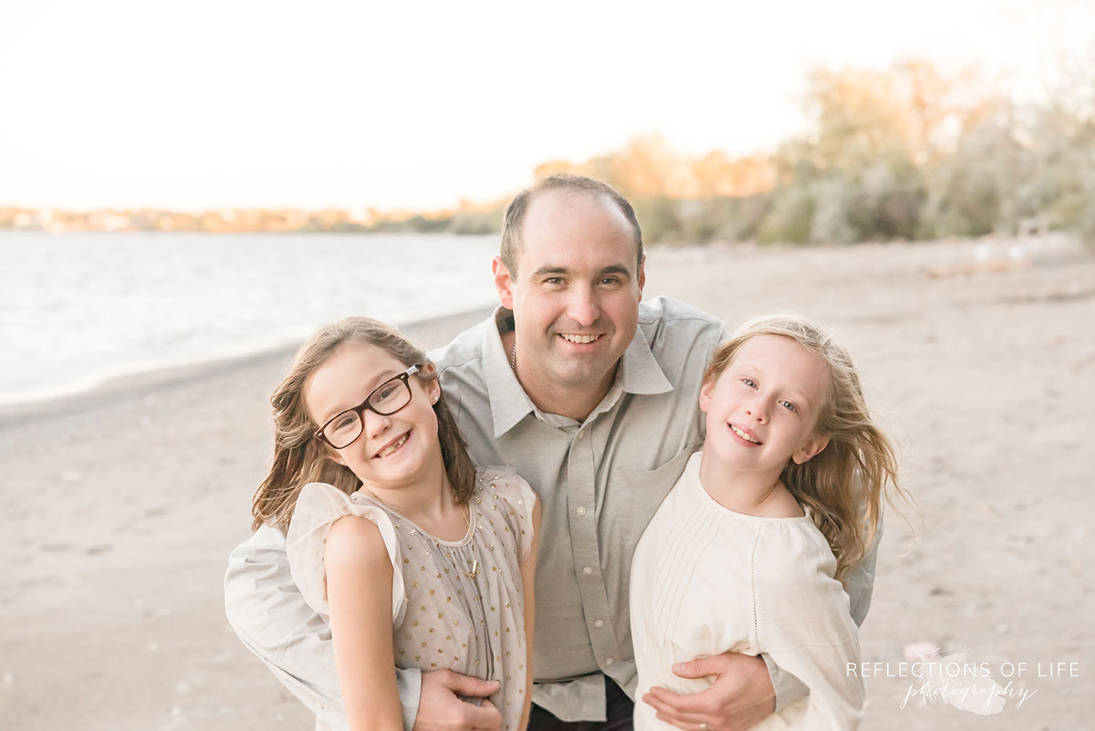 father hugging two daughters