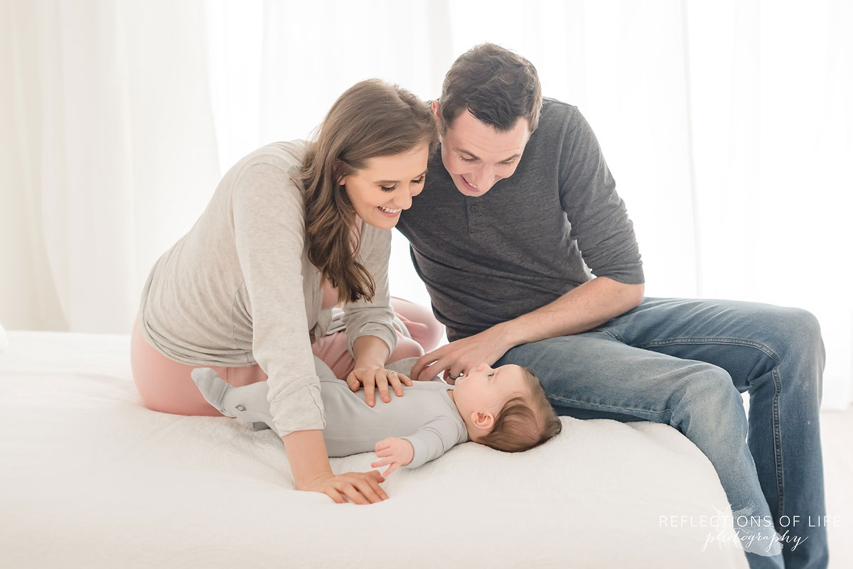 parents smiling at baby in white studio