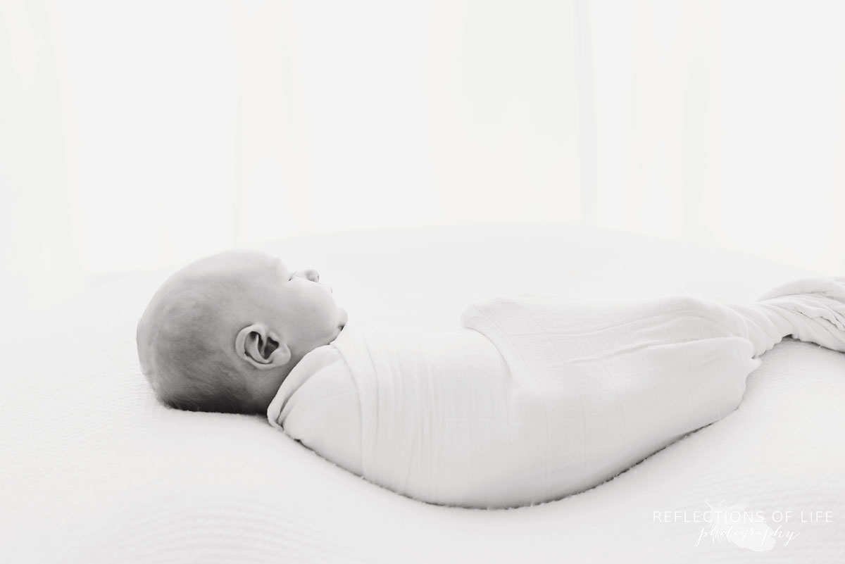 baby wrapped up in white studio