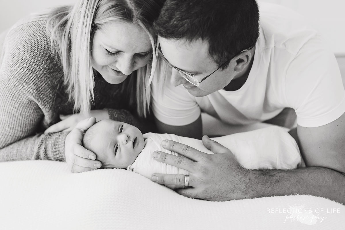 husband and wife smiling at baby