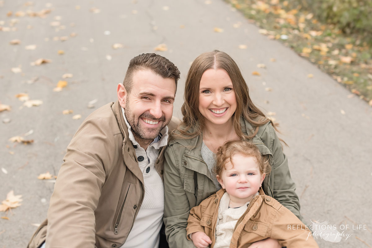 family of three sitting on fall trail