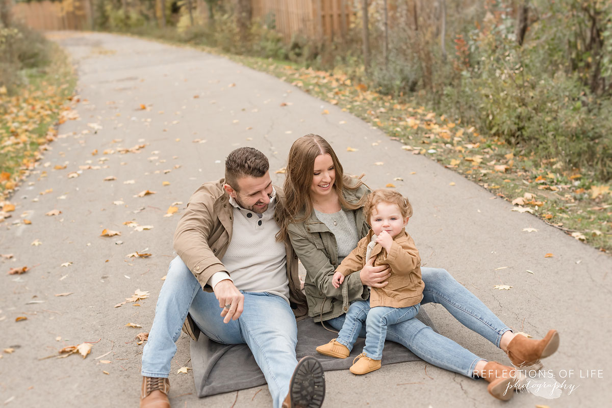 family sitting on walkway in the fall time